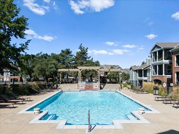 A large swimming pool surrounded by trees and a building. at Somerset Oaks Apartment Homes, Olathe, Kansas